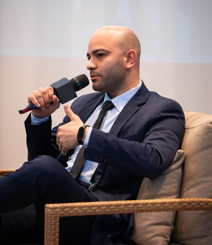 Caio Nascimento em conversa, gesticulando com a mão livre